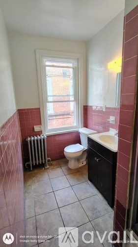 A bathroom with a toilet, sink, and window.