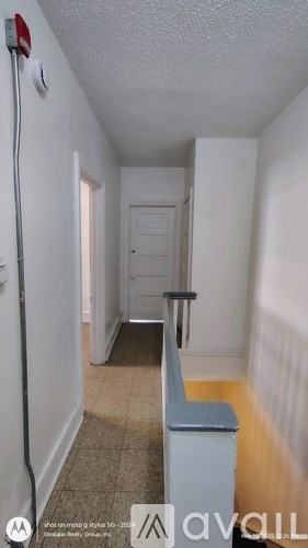A hallway with a bench and a door at the end.