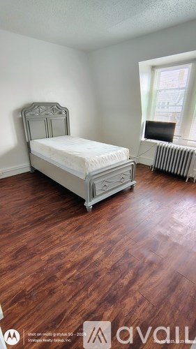 A bedroom with a bed, chair, and window.