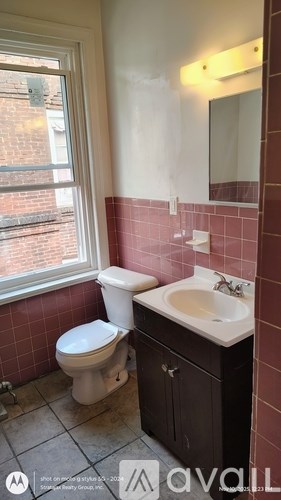 A bathroom with a toilet, sink, and a window.