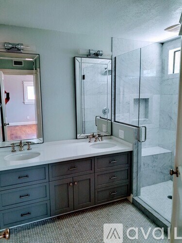 A bathroom with a sink, mirror, and shower.