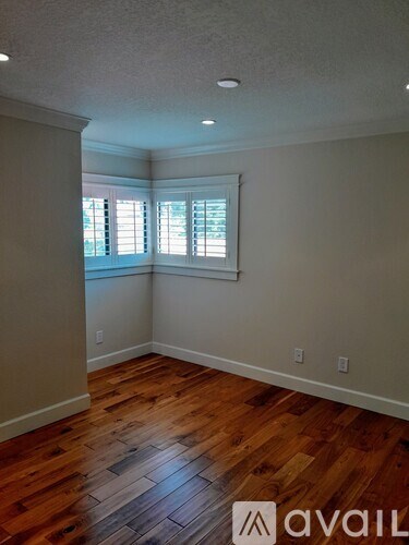 A room with wooden floors and a window with blinds.