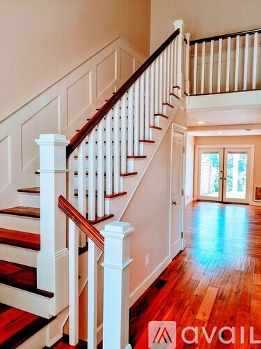 A wooden staircase with white railings and a doorway at the top.