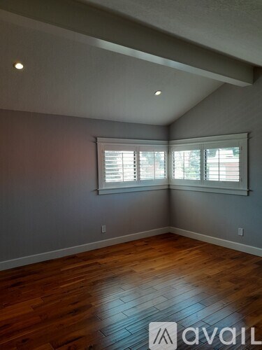 A room with wooden floors and a window with blinds.