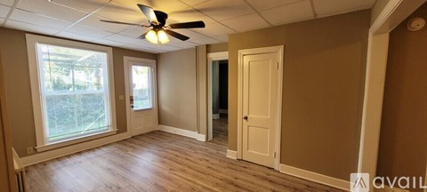 A room with a ceiling fan and a door.