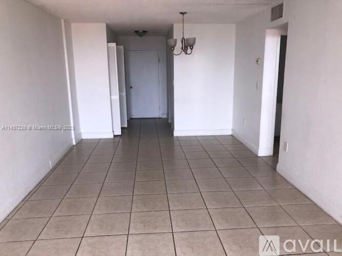 A spacious room with tiled flooring and white walls.
