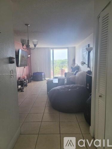 A living room with a couch, ottoman, and television.