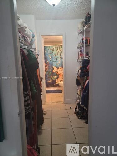 A hallway with a doorway leading to a room with a painting on the wall.