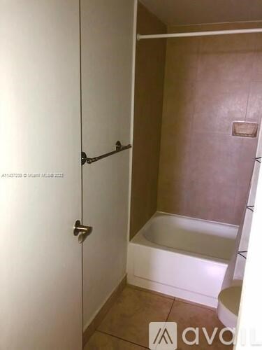 A bathroom with a white door and a bathtub.