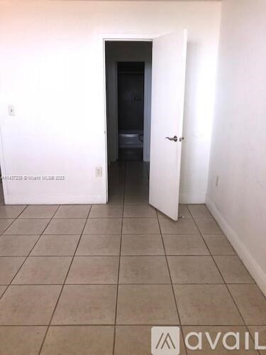 A room with a white door and a tiled floor.