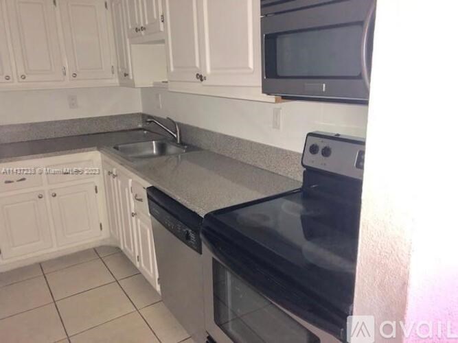 A kitchen with black appliances and white cabinets.