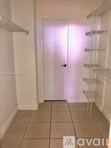 A hallway with a white door and shelves on the wall.