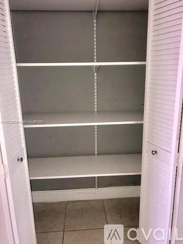 A white closet with three shelves and a door.