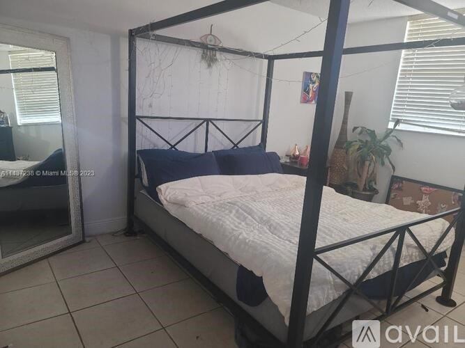 A bed with a white comforter and a black metal frame in a room.