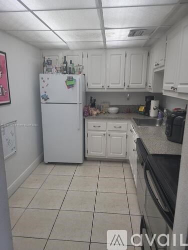 A kitchen with white cabinets and a white fridge.