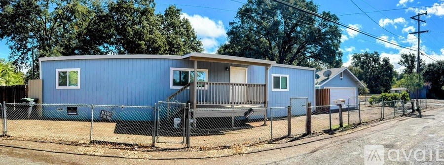 A blue house with a porch and a fence in front of it.