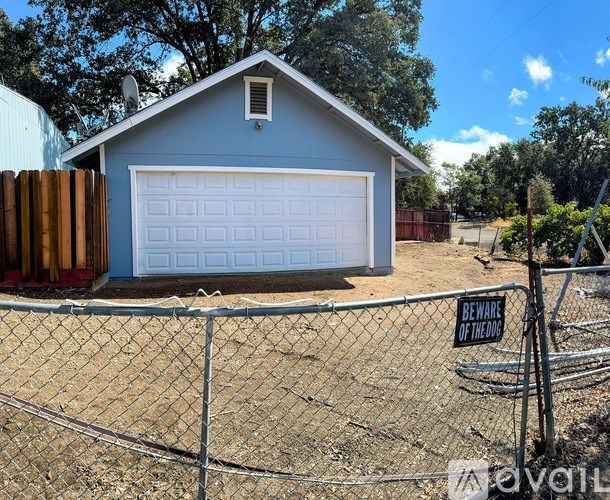 A garage with a white door is behind a chain link fence with a sign that says "BEWARE OF THE DUCK".