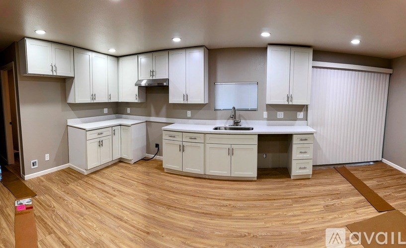 A kitchen with white cabinets and a wooden floor.