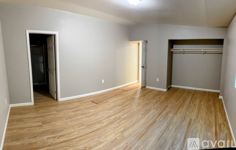 A room with wooden flooring and two doors, one of which is open.