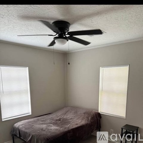 A room with a ceiling fan and a bed.