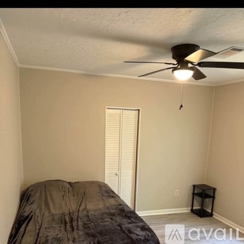 A bedroom with a bed, a ceiling fan, and a small table.