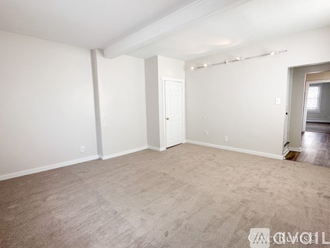A spacious room with beige carpeting and white walls.