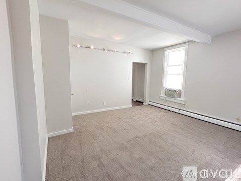 A spacious room with carpeted floor and a window.