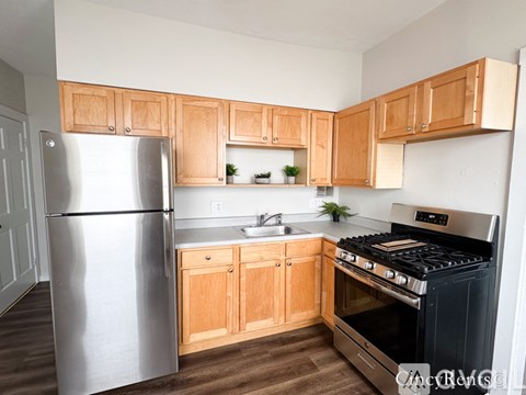 A kitchen with wooden cabinets and a stainless steel refrigerator.