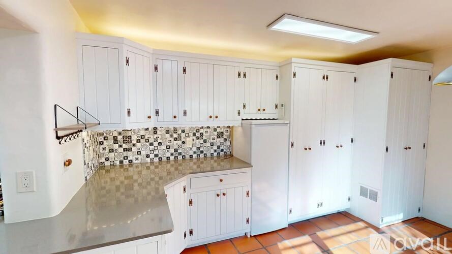 A kitchen with white cabinets and a tile backsplash.