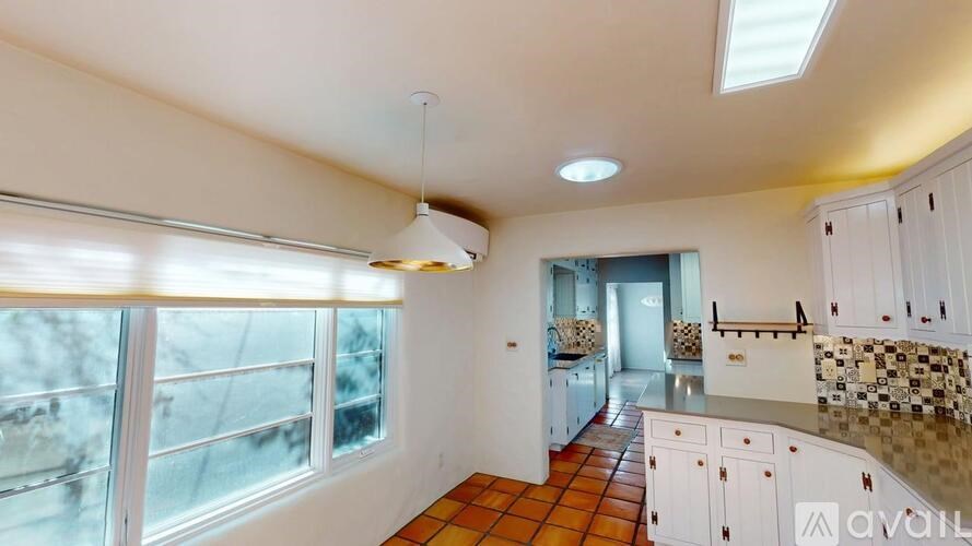 A kitchen with white cabinets and a tiled floor.