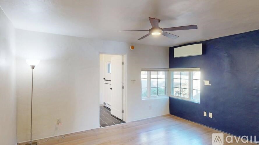 A room with a ceiling fan and a door leading to another room.