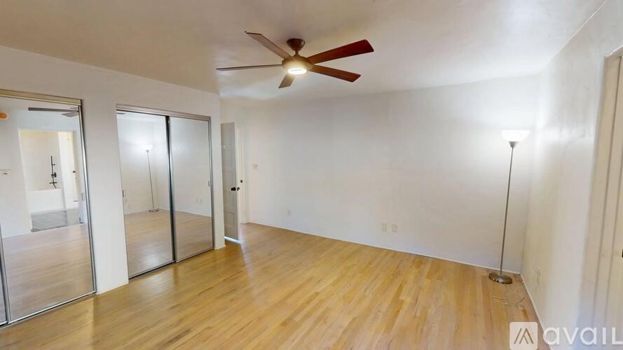 A room with a ceiling fan and wooden flooring.