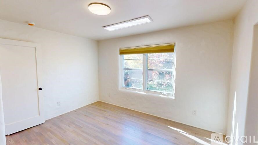 A room with a window and a door is available for rent.