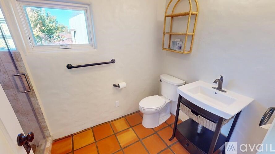 A bathroom with a toilet, sink, and a window.