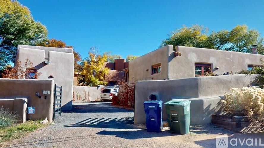 A house with a blue and green trash bin in front of it.