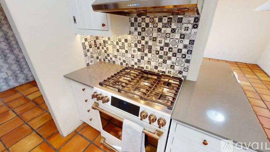 A kitchen with a tile backsplash and a stove top oven.