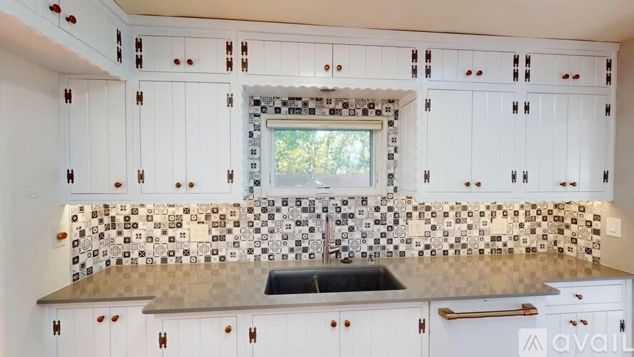 A kitchen with white cabinets and a checkered backsplash.