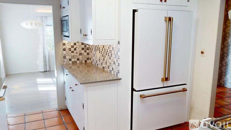 A kitchen with a white fridge and a tiled floor.