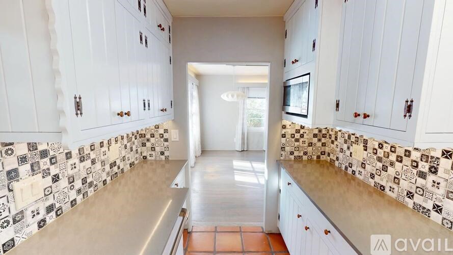 A kitchen with white cabinets and a tile backsplash.