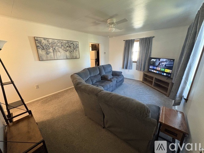 A living room with a grey couch and a television on a stand.