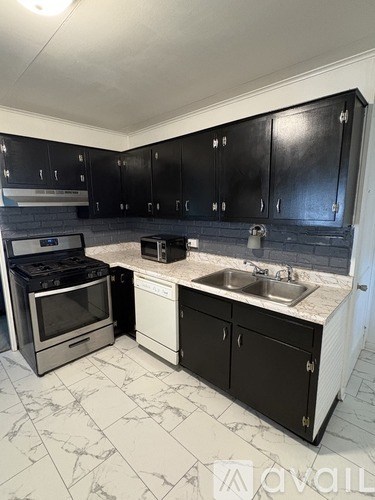 A kitchen with black cabinets and a white marble countertop.