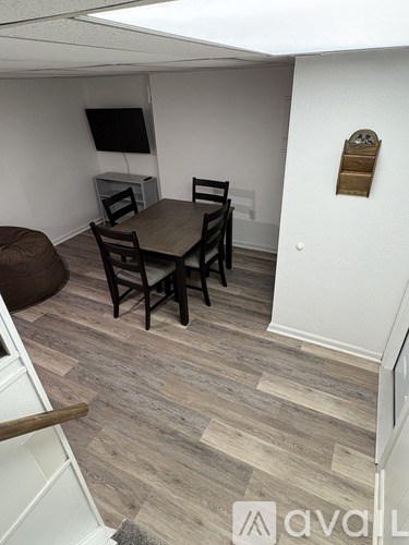 A room with a wooden table and chairs, a television, and a white cabinet.