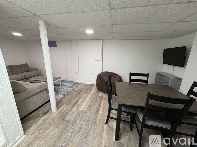 A living room with a couch, chairs, and a television.