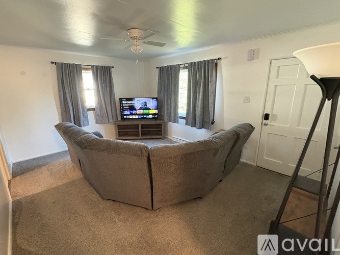 A living room with a large couch and a television on a stand.