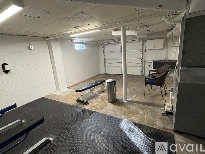 A gym with a black mat, a bench, and a chair.