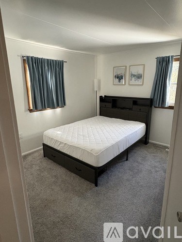 A bedroom with a bed, nightstand, and two pictures on the wall.