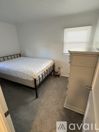 A bedroom with a bed, a wardrobe, and a window with blinds.