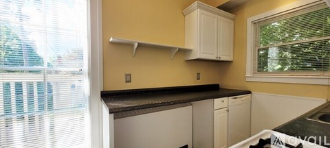 A kitchen with white cabinets and a black countertop.