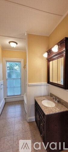 A bathroom with a sink, mirror, and a window.