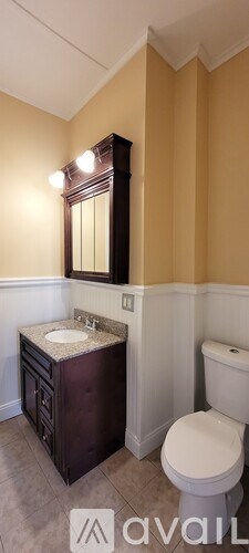 A bathroom with a toilet, sink, and mirror.